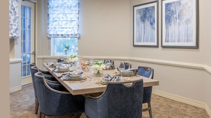 Stylishly set dining table with blue chairs and artwork on the walls.