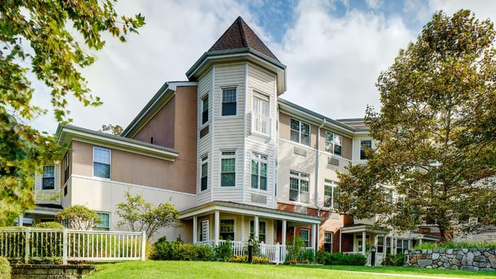 View of Atria Woodlands senior living facility from the lawn