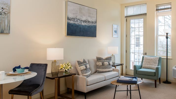 A cozy living room with a sofa, chairs, and natural light.
