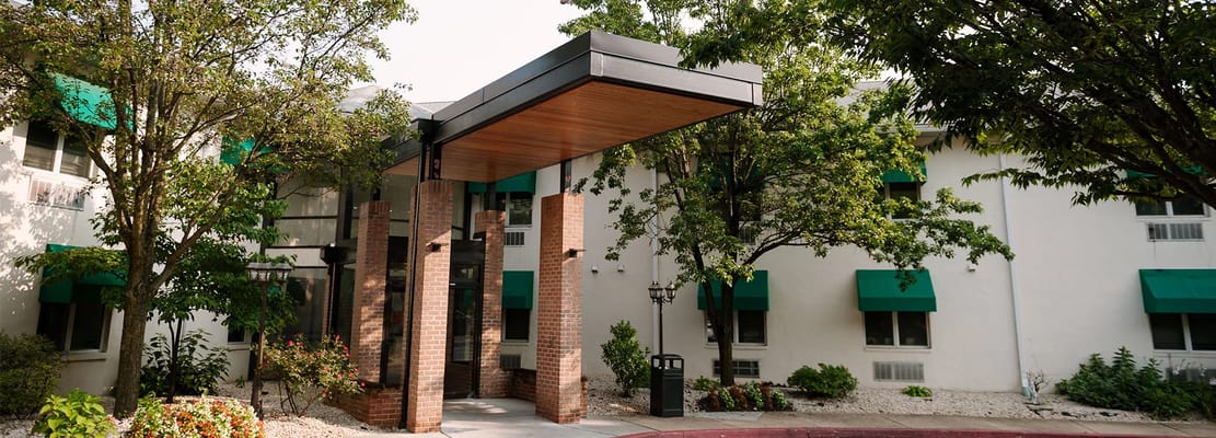 Front entrance with brick columns, canopy, and greenery.
