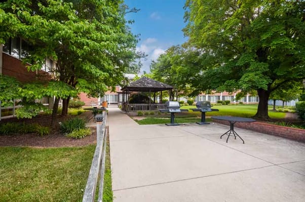 Outdoor gazebo area with green spaces and grills