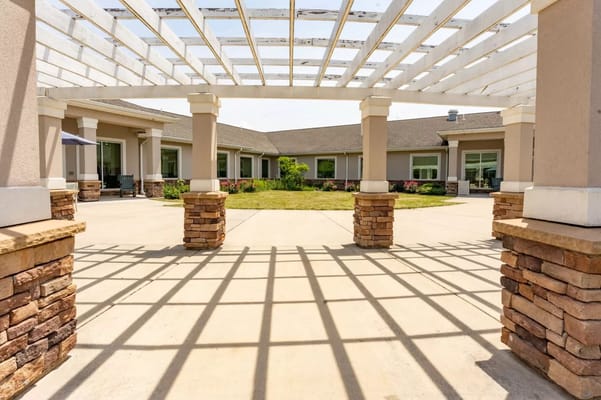 Outdoor courtyard area with shaded arches and plants