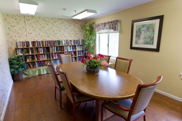 A cozy common area with bookshelves and a dining table
