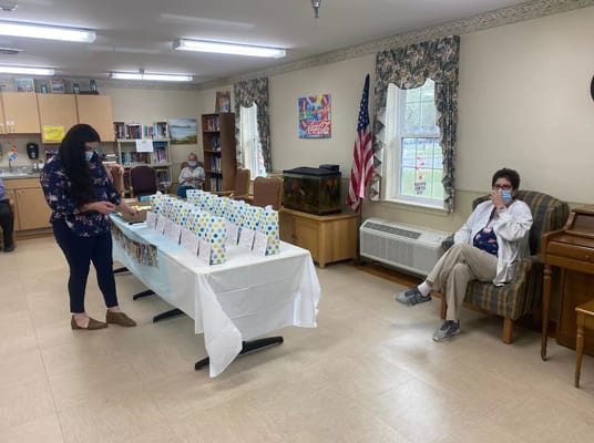 Staff member preparing for a celebration in a community room with residents in the background