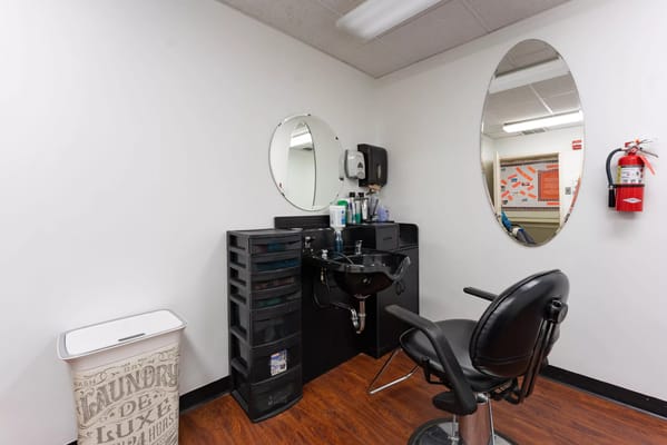 Hair salon station with a black chair and mirror