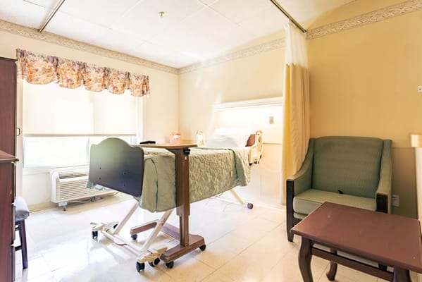 A well-lit room with a hospital bed and seating area.