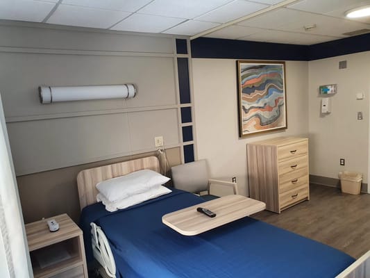 A neatly arranged resident room with a bed and furniture