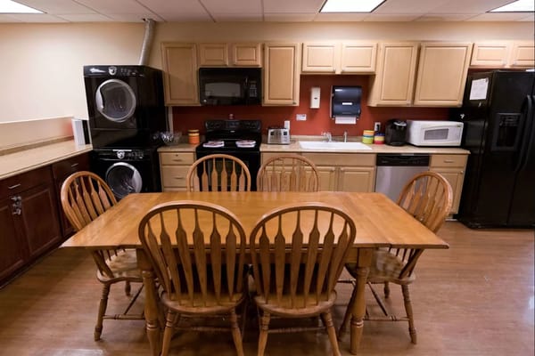 Dining area in a facility kitchen with a wooden table and chairs
