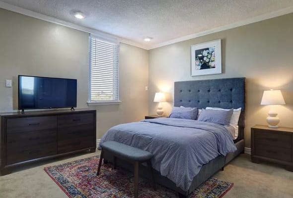 A well-decorated private room with a bed and TV