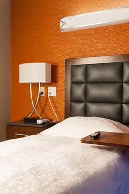 Bedroom with a black tufted headboard and lamp
