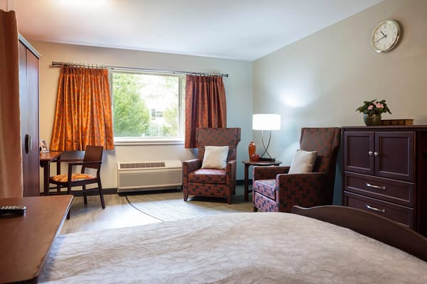 A cozy room with two chairs, a desk, and a window at Avalon Federal Way Care Center.