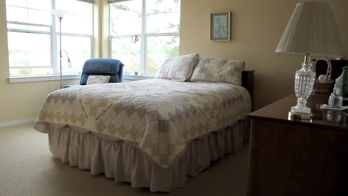 Brightly lit resident bedroom with a bed and chair