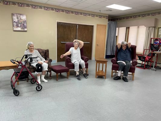 Residents participating in a seated exercise activity in a common area