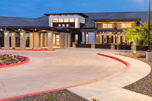 The entrance area of Avanti Living at Peoria with landscaped flowers and modern architecture.
