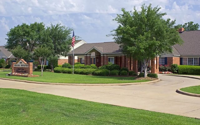 Front view of Azalea Estates of Monroe with landscaped entrance and flag.