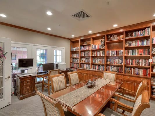 Cozy library with wooden shelves filled with books and a wooden table in the center