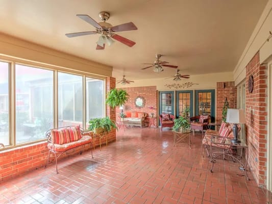 Sunroom with comfortable seating and plants, featuring large windows.