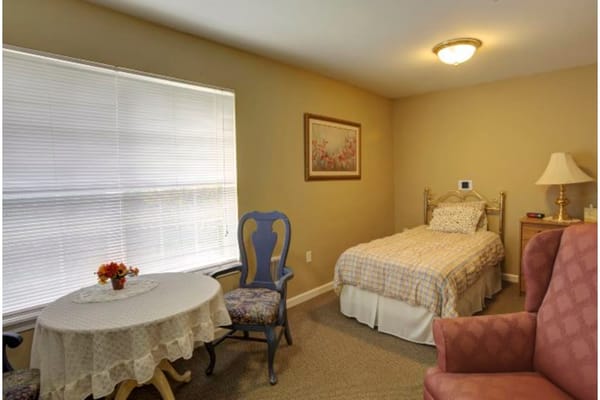A cozy resident room with a bed and seating area.
