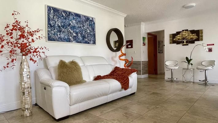 A cozy living room with a white sofa, decorative art, and modern chairs.
