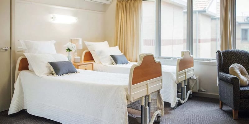 A comfortable resident room with two beds and natural light