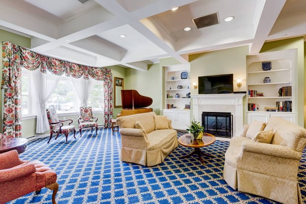 Lounge area with floral curtains, a piano, and comfortable seating.