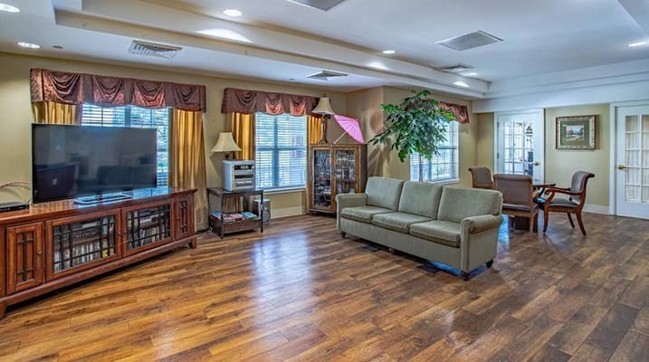 Spacious living area with a sofa, TV, and natural light