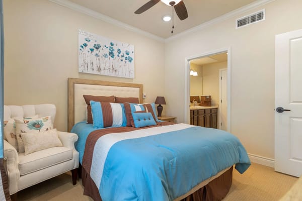 A cozy bedroom featuring a large bed with decorative pillows and a comfortable armchair.