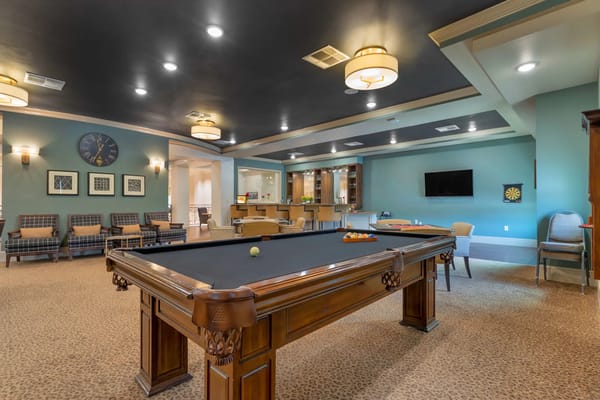 A spacious game room featuring a pool table and comfortable seating.