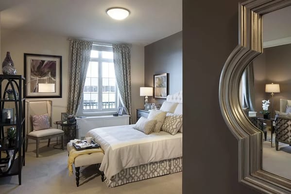 A stylish bedroom featuring a bed, decorative pillows, and a window with natural light.