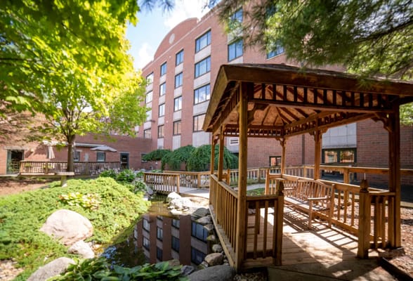 Wooden gazebo overlooking a serene pond and garden at Bernard L Strange Pavilion.