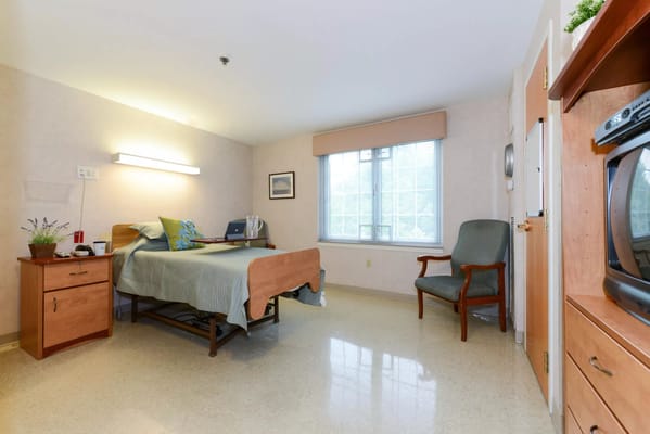 A private resident room with a bed and chair