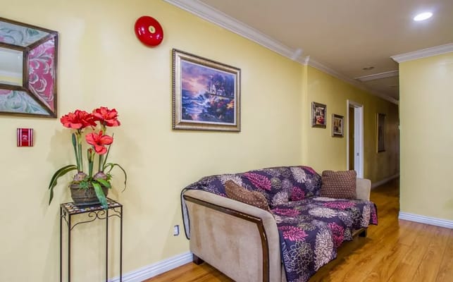 A cozy living room featuring a sofa, flower vase, and artwork