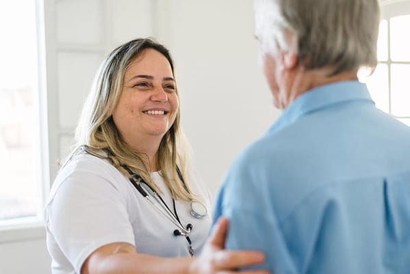 A caregiver smiling at a senior resident in an indoor setting