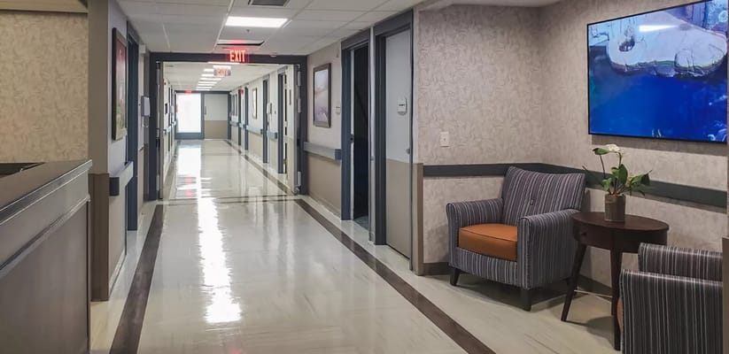 Clean and well-lit hallway with a chair and TV