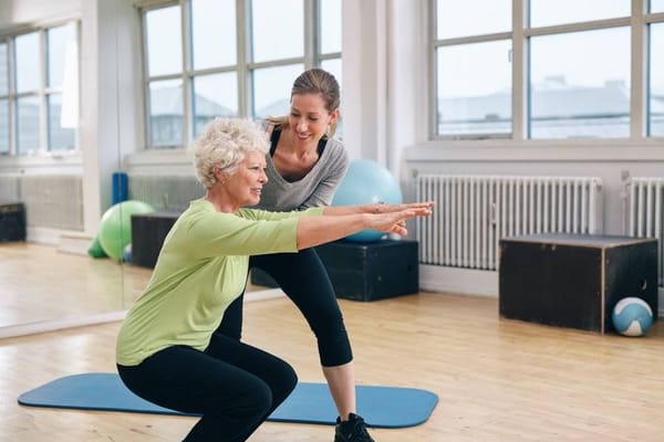 Resident exercising with staff support in a bright activity room