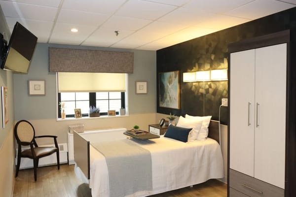 A well-furnished private resident room with a bed and chair