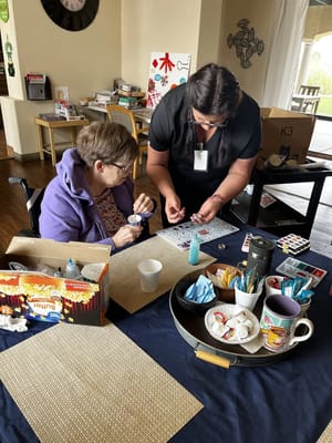 A staff member assists a resident in an art activity.