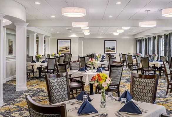 Bright dining room set up for meals with flowers and table settings