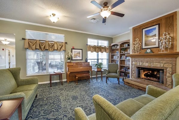 A cozy common area with seating, a piano, and a fireplace