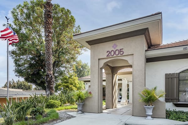 Entrance of Brookdale Corona with landscaping and flag