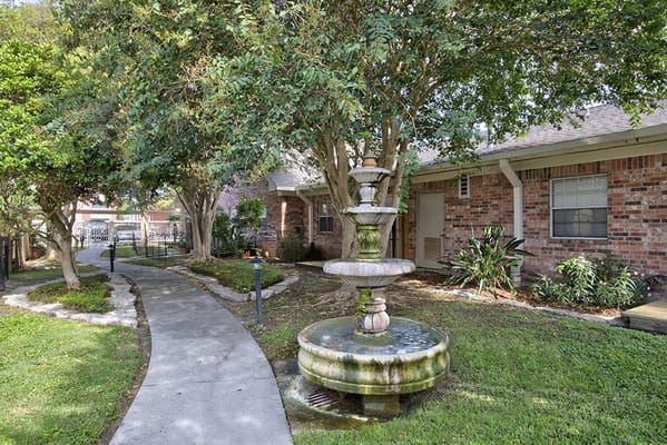 A pathway and fountain in a landscaped area