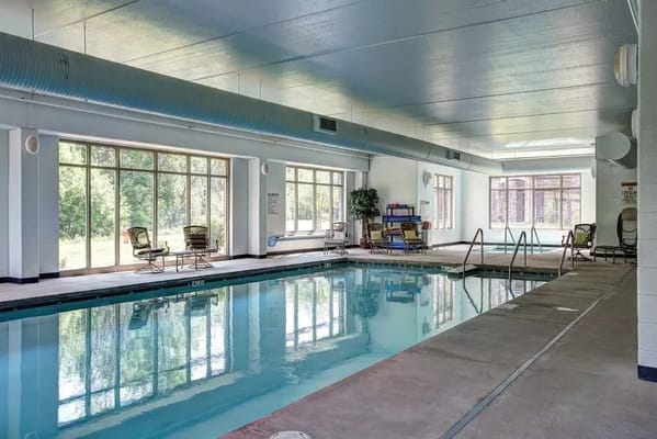 Indoor swimming pool with seating area and large windows