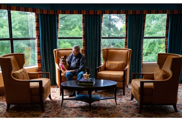 Resident sitting in a cozy lounge with a dog