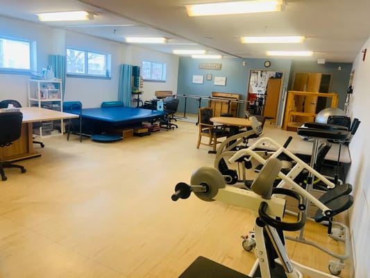 Physical therapy room with exercise equipment and tables