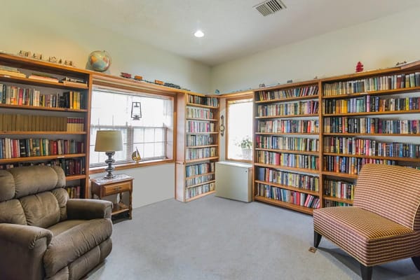 Library with bookshelves, armchair, and lamp in a reading nook