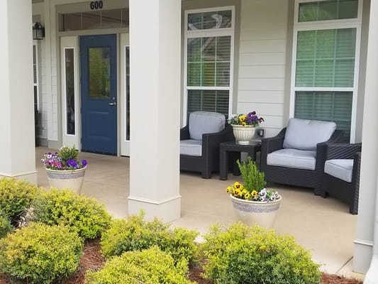Two comfortable chairs with potted flowers on a porch