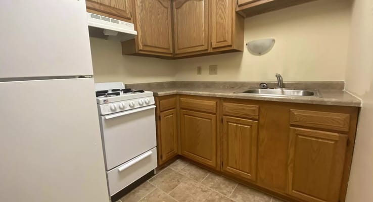 Compact kitchen with white appliances and wooden cabinets