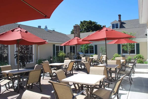 Sunny outdoor patio with red umbrellas and seating