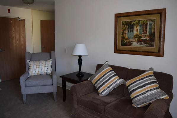 Cozy living room with a sofa, chair, lamp, and artwork