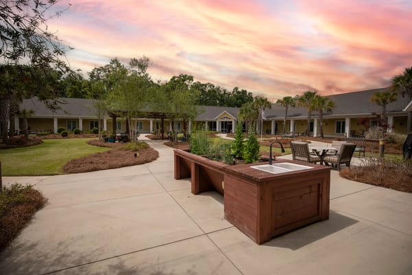 A garden area featuring raised planting beds and seating in a senior living facility.